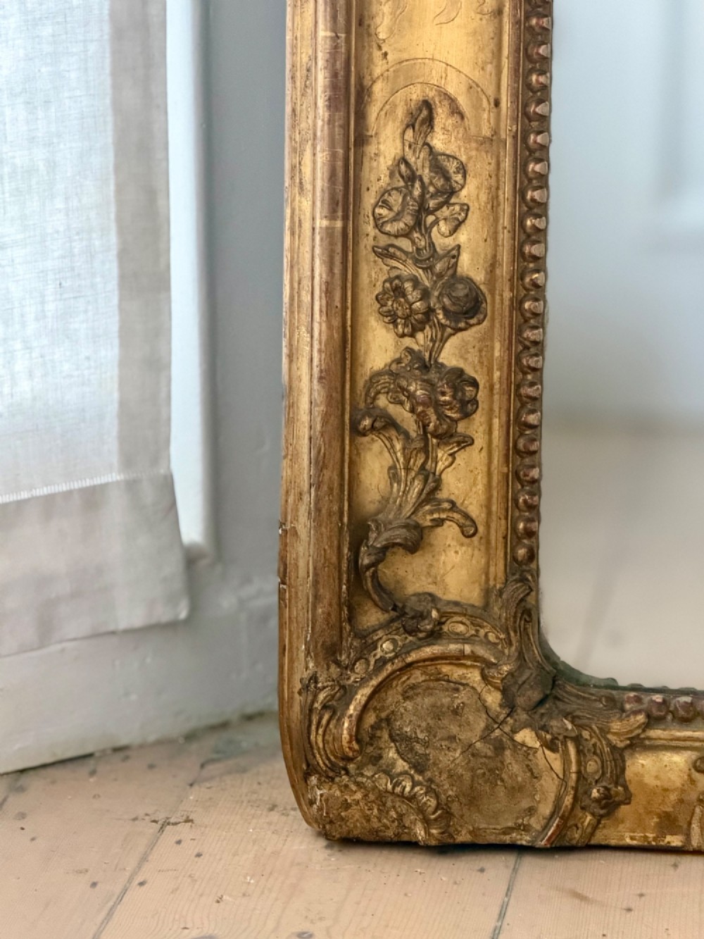 A large rectangular French Napoleon III giltwood leaner mirror featuring ornate carved foliate mouldings and an aged glass plate. View V