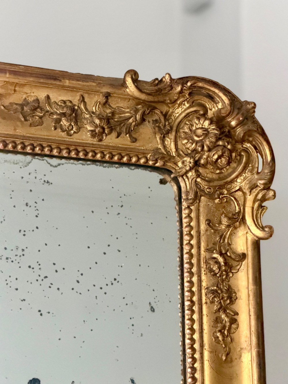 A large rectangular French Napoleon III giltwood leaner mirror featuring ornate carved foliate mouldings and an aged glass plate. View VII