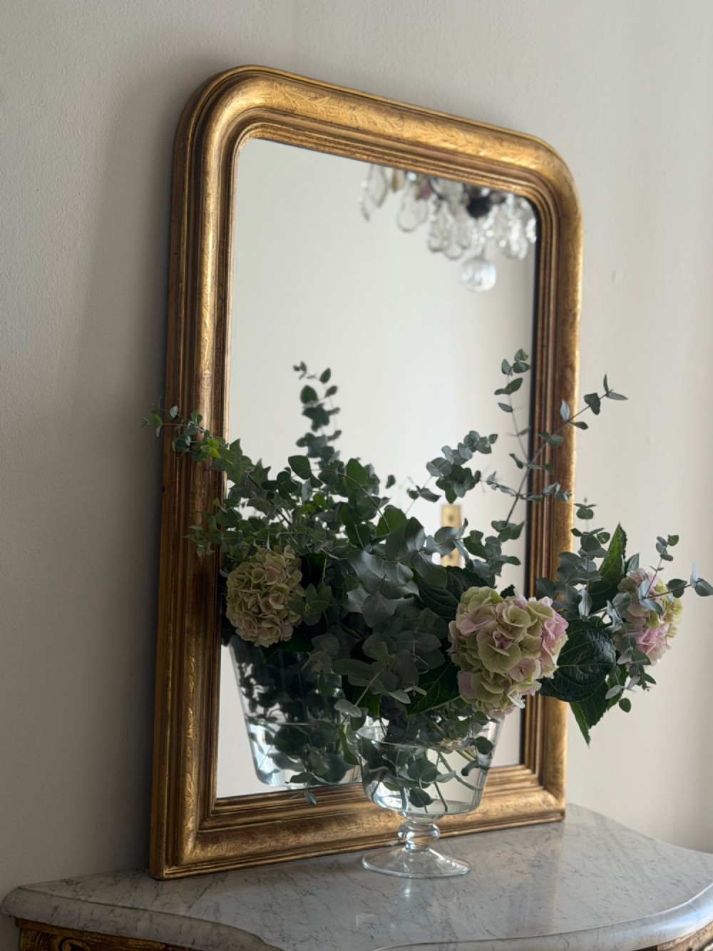 An antique French Louis Philippe wall mirror featuring a rectangular gilded frame with rounded upper corners, subtle etched foliate patterns, and a mercury glass plate. View II