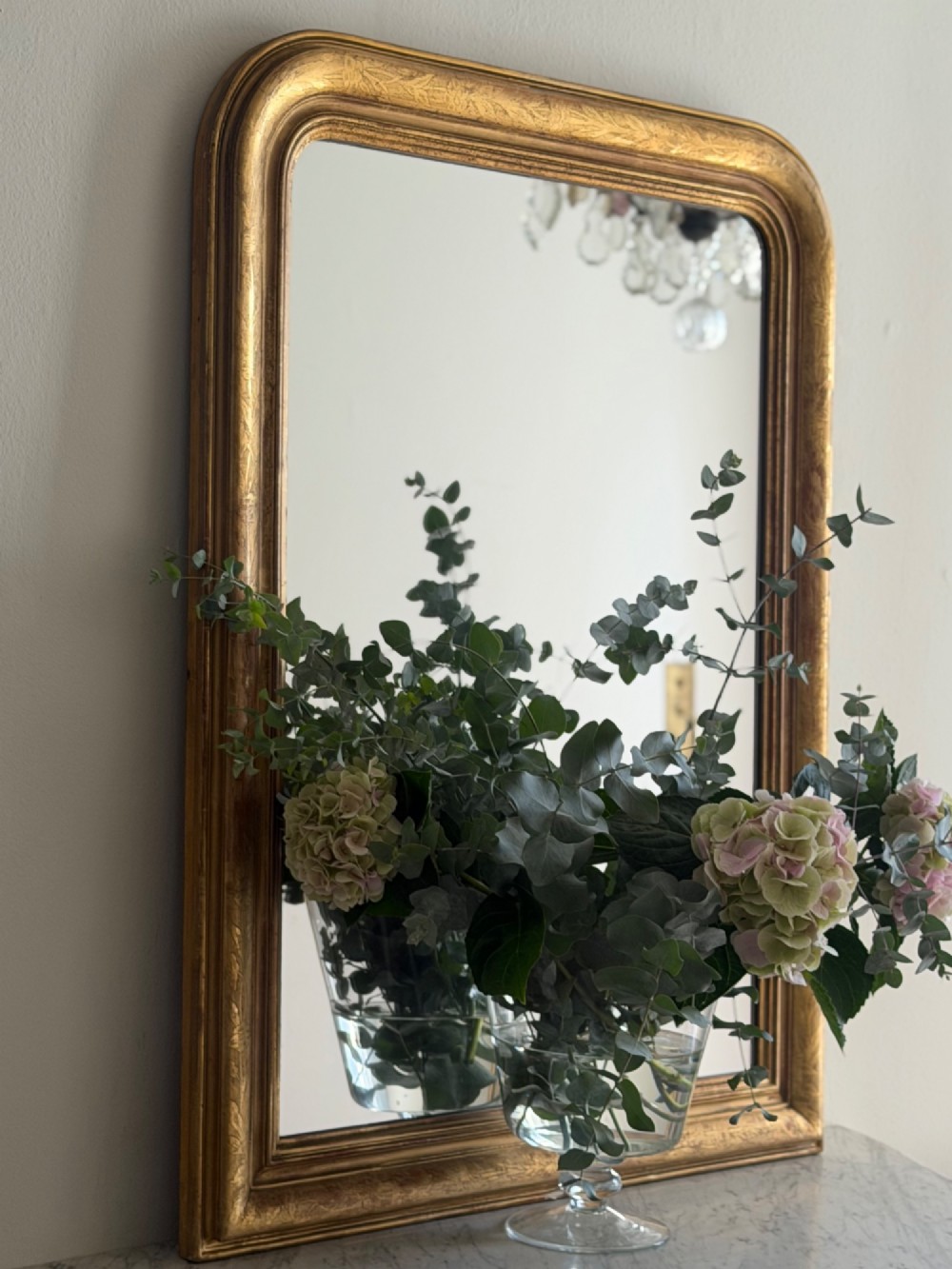An antique French Louis Philippe wall mirror featuring a rectangular gilded frame with rounded upper corners, subtle etched foliate patterns, and a mercury glass plate. View III