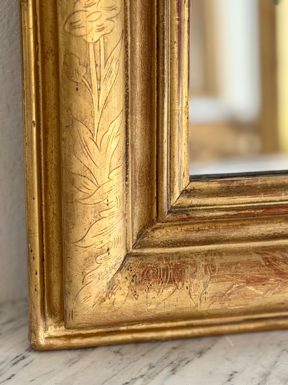 An antique French Louis Philippe wall mirror featuring a rectangular gilded frame with rounded upper corners, subtle etched foliate patterns, and a mercury glass plate. View VI