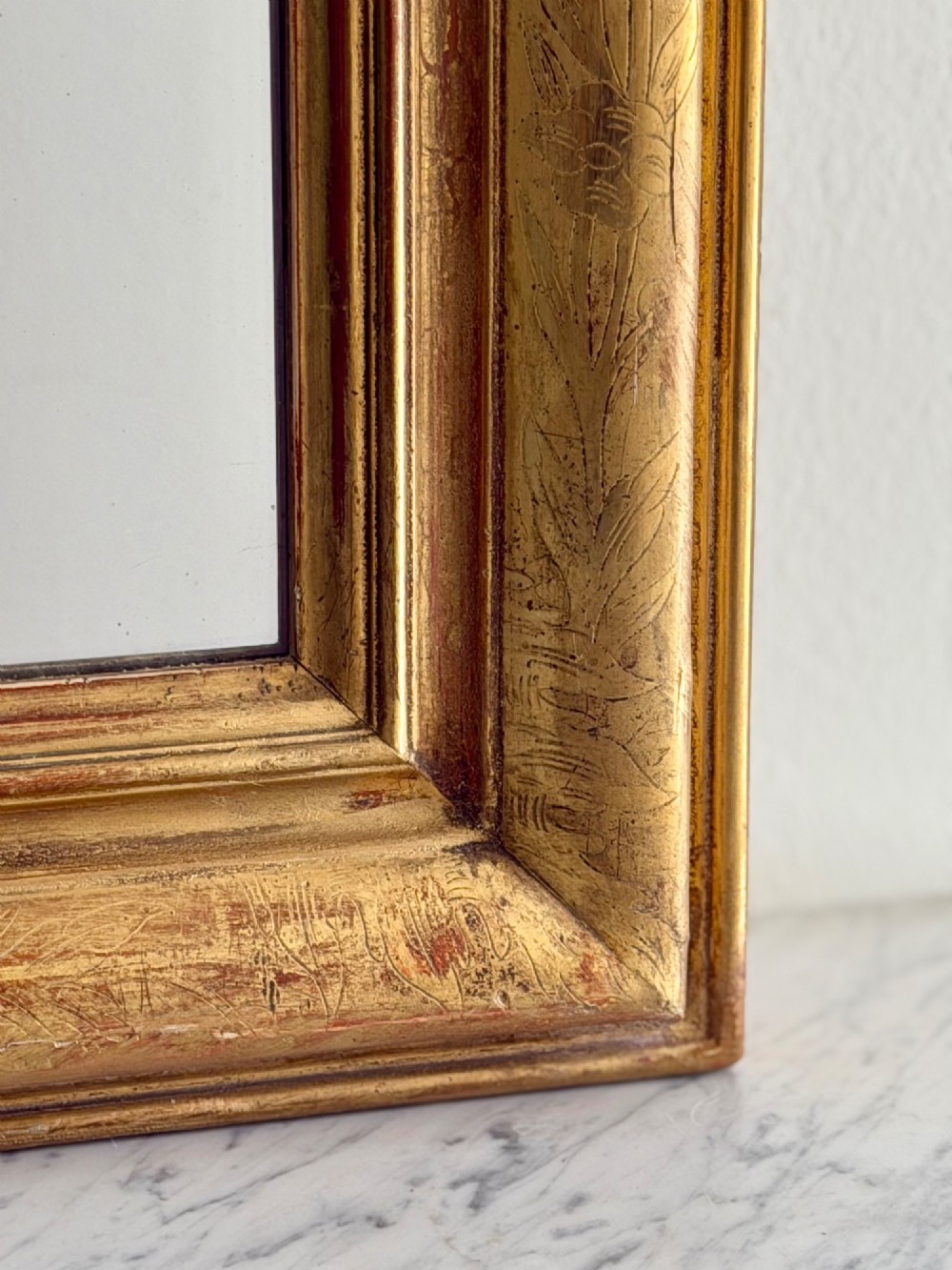 An antique French Louis Philippe wall mirror featuring a rectangular gilded frame with rounded upper corners, subtle etched foliate patterns, and a mercury glass plate. View VII