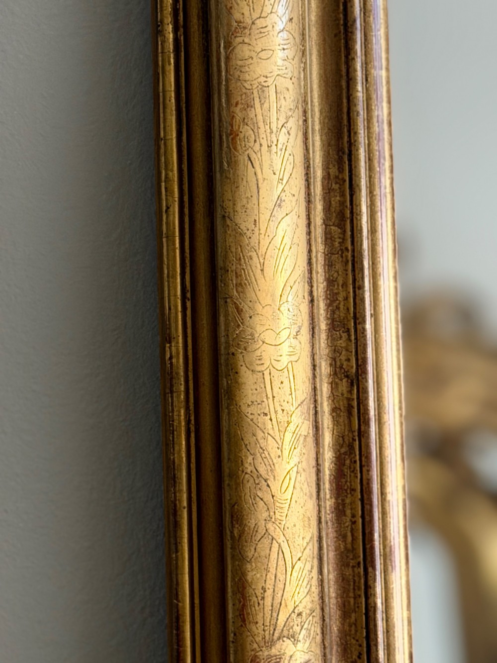 An antique French Louis Philippe wall mirror featuring a rectangular gilded frame with rounded upper corners, subtle etched foliate patterns, and a mercury glass plate. View VIII