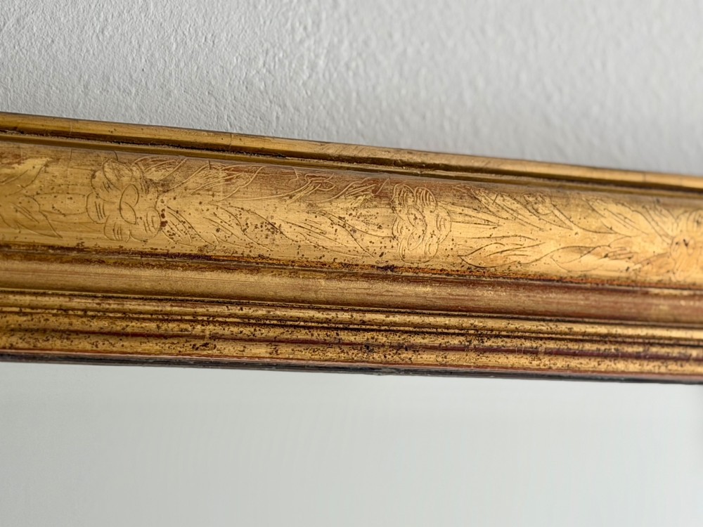 An antique French Louis Philippe wall mirror featuring a rectangular gilded frame with rounded upper corners, subtle etched foliate patterns, and a mercury glass plate. View IX
