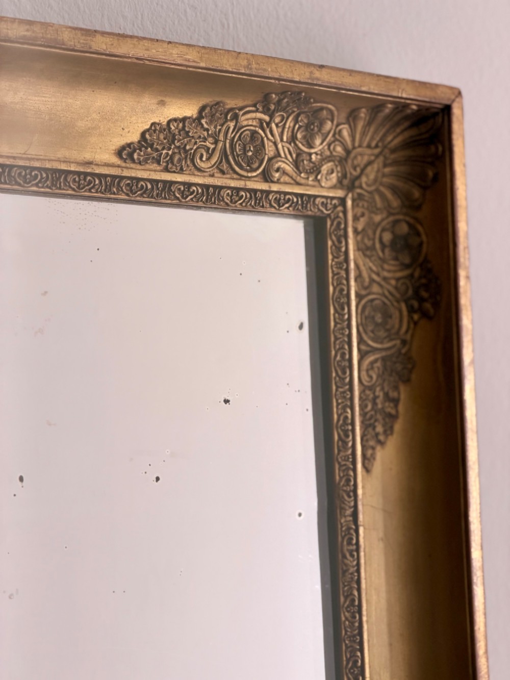 A rectangular antique French giltwood mirror featuring carved corner spandrels and a foxed glass plate. View IV