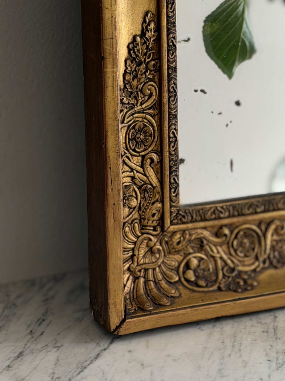 A rectangular antique French giltwood mirror featuring carved corner spandrels and a foxed glass plate. View V