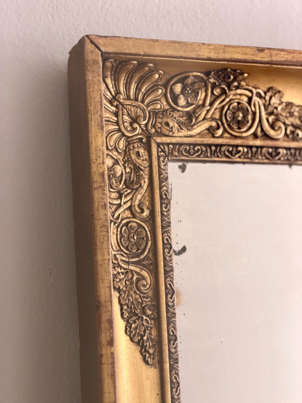 A rectangular antique French giltwood mirror featuring carved corner spandrels and a foxed glass plate. View VII