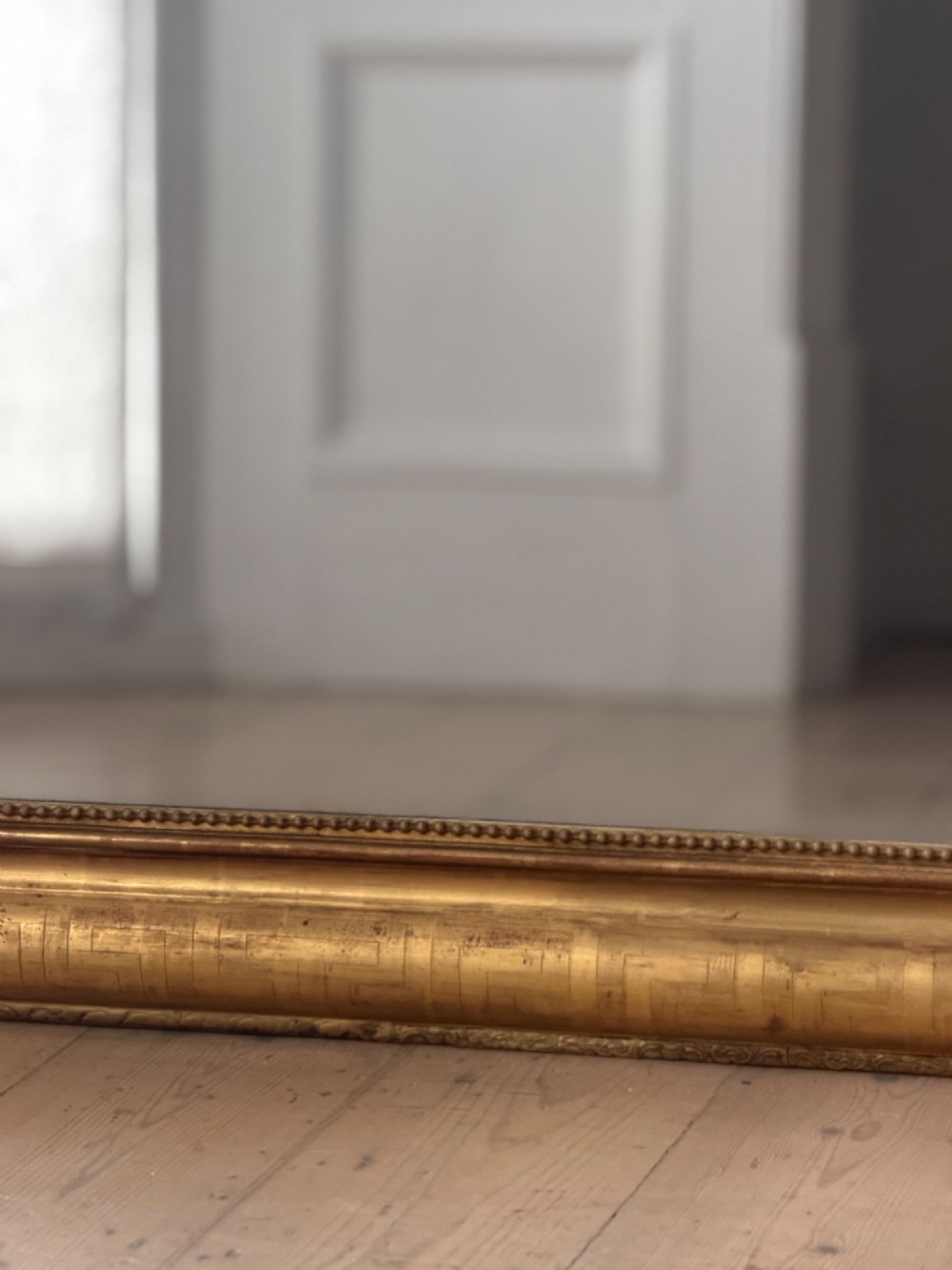 A large French Louis XV style giltwood mirror featuring an ornate rocaille cresting, foliate scrolls, and mercury glass mirror plate. View IV