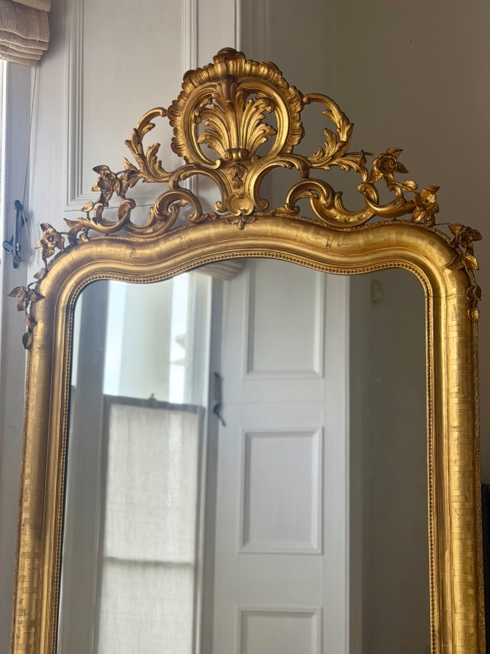 A large French Louis XV style giltwood mirror featuring an ornate rocaille cresting, foliate scrolls, and mercury glass mirror plate. View V