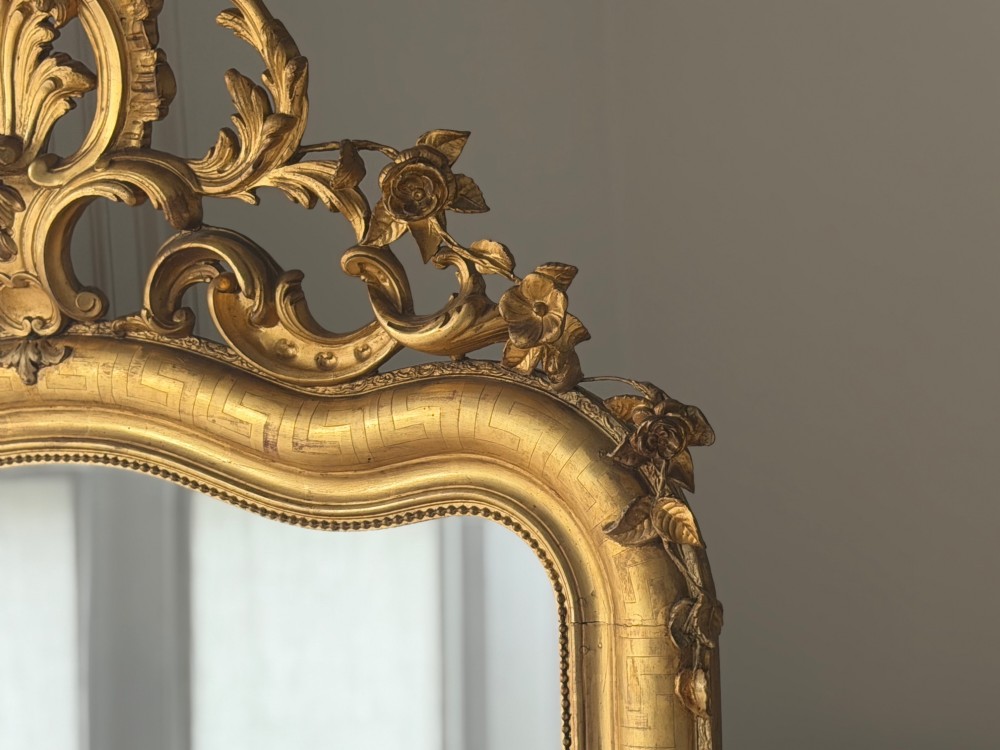 A large French Louis XV style giltwood mirror featuring an ornate rocaille cresting, foliate scrolls, and mercury glass mirror plate. View VIII