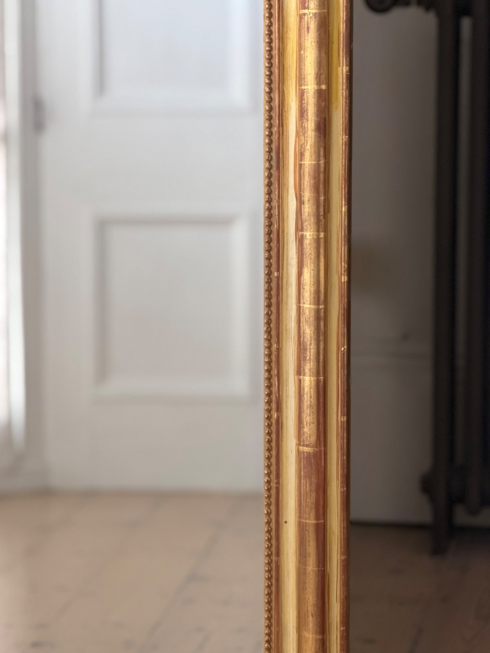 A tall rectangular French Louis Philippe wall mirror with rounded top corners, an elaborate carved shell cresting, a gold gilt frame over red gesso, and a beaded inner trim. View II