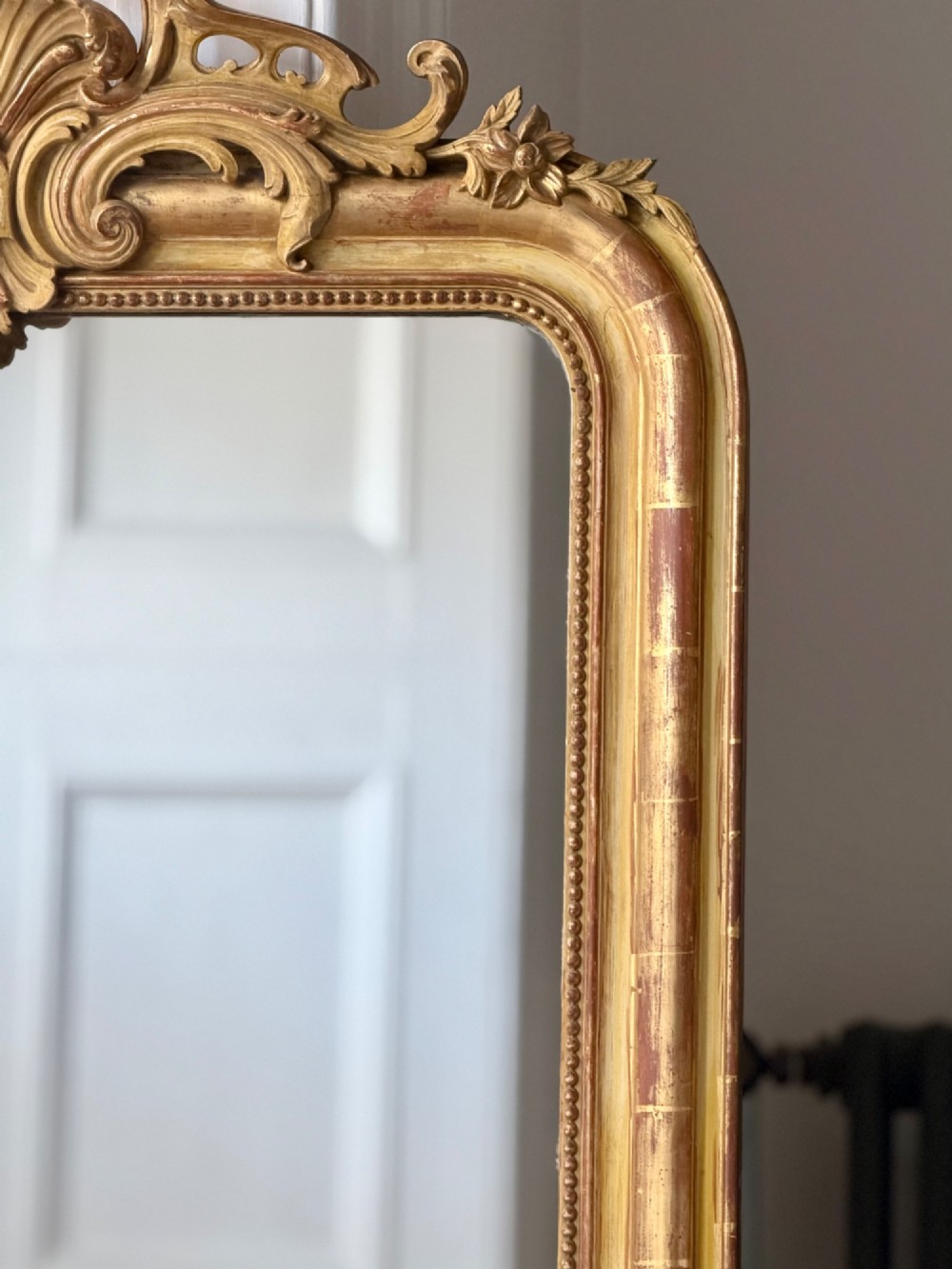 A tall rectangular French Louis Philippe wall mirror with rounded top corners, an elaborate carved shell cresting, a gold gilt frame over red gesso, and a beaded inner trim. View III