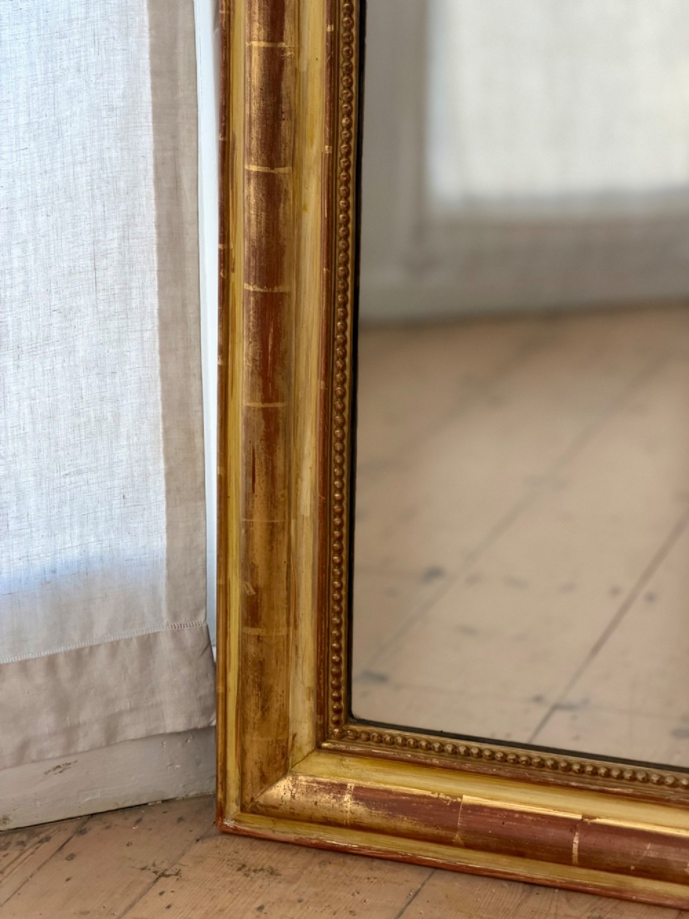 A tall rectangular French Louis Philippe wall mirror with rounded top corners, an elaborate carved shell cresting, a gold gilt frame over red gesso, and a beaded inner trim. View VII