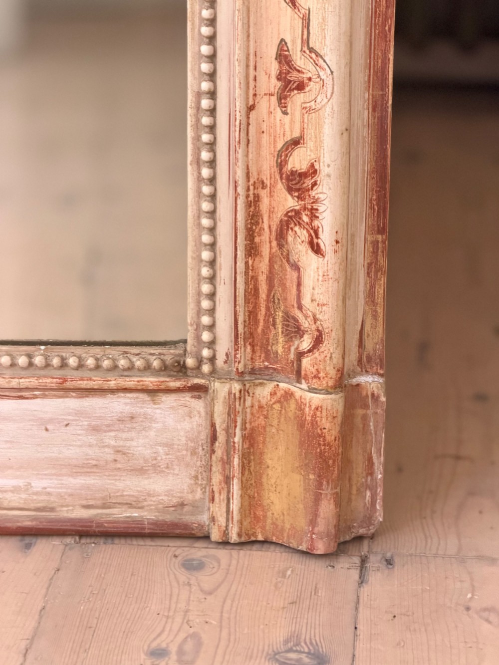An antique French mirror featuring an arched top frame with a carved cresting and distressed off-white gesso finish. View V
