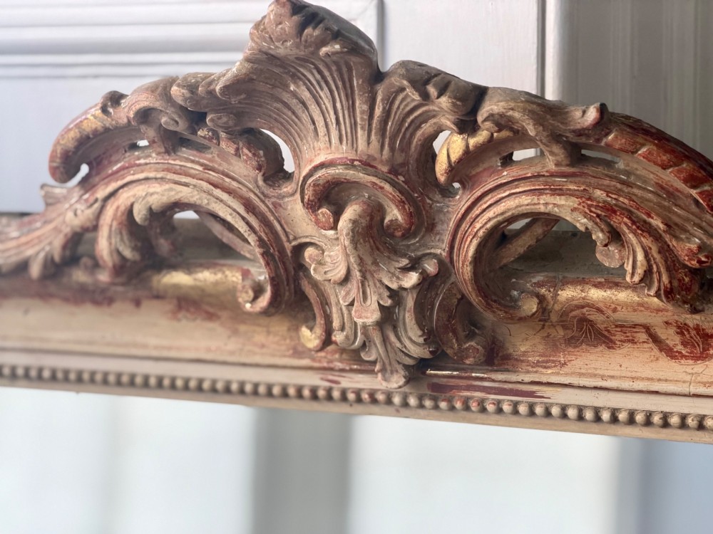 An antique French mirror featuring an arched top frame with a carved cresting and distressed off-white gesso finish. View IX