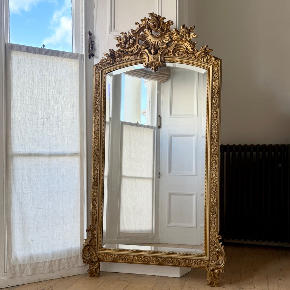 A large French gilded wood frame mirror featuring an arched top, a carved scroll cresting, and bevelled edge glass. View II
