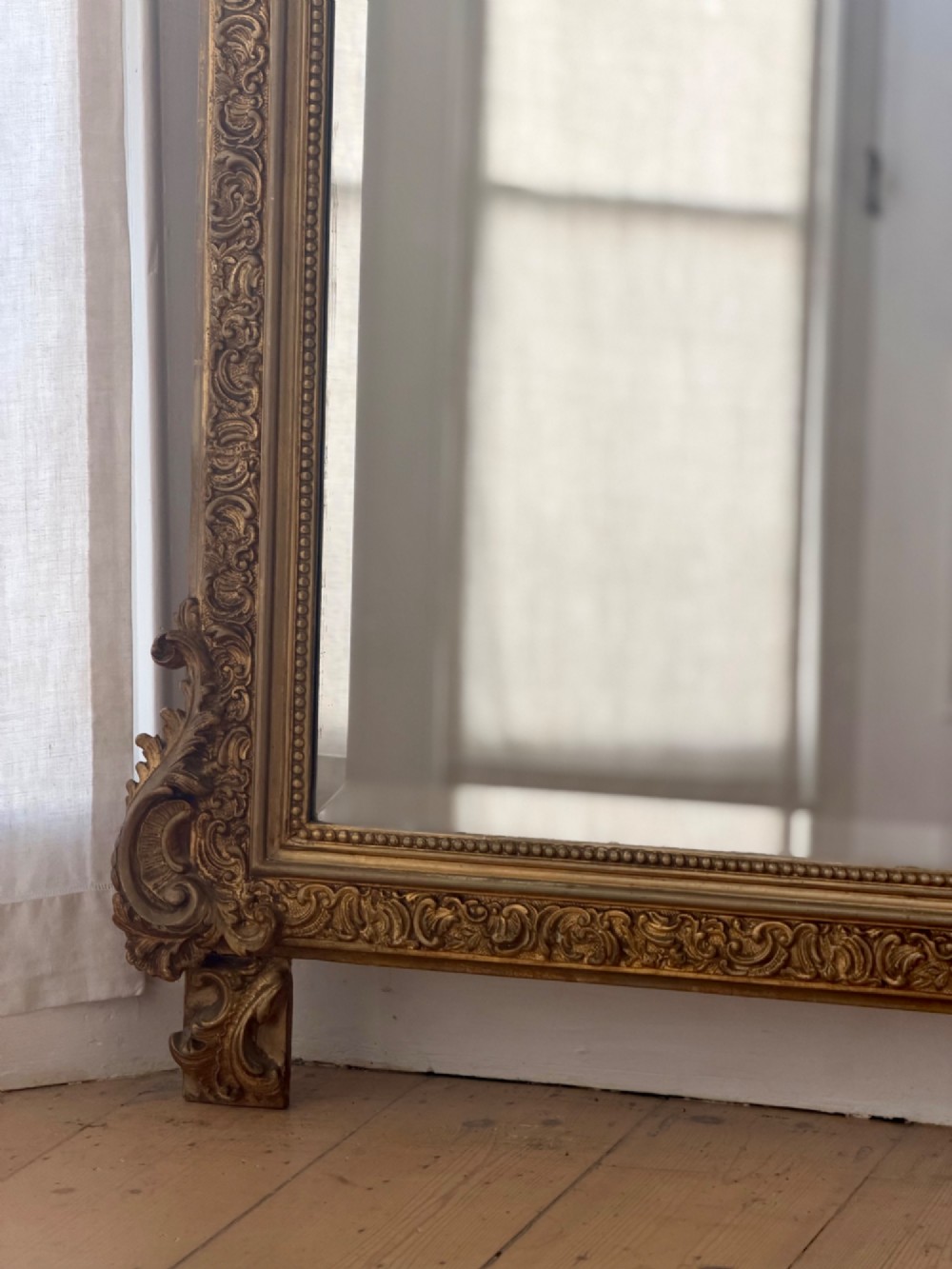 A large French gilded wood frame mirror featuring an arched top, a carved scroll cresting, and bevelled edge glass. View III