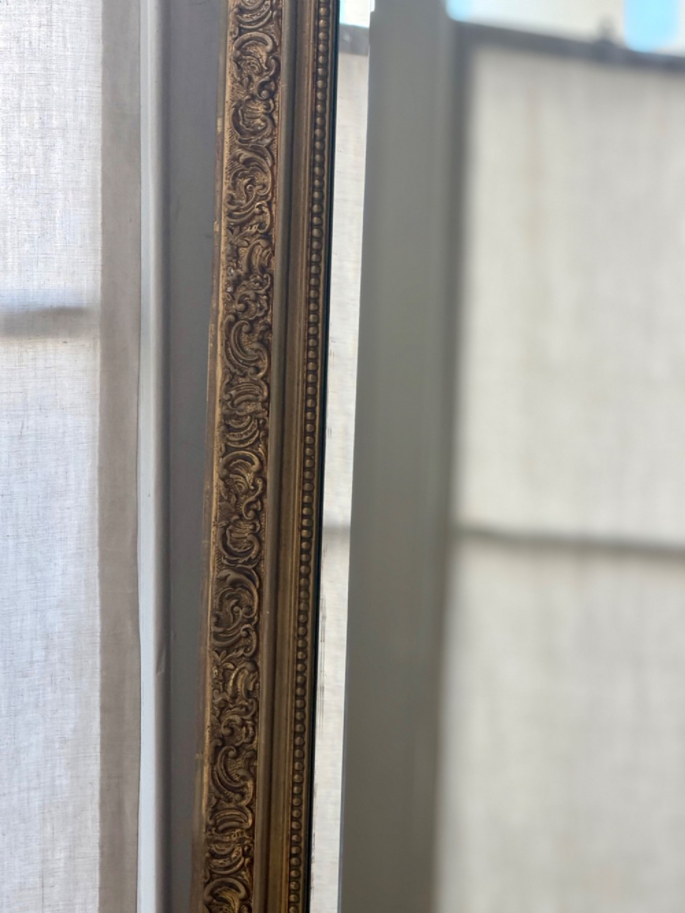 A large French gilded wood frame mirror featuring an arched top, a carved scroll cresting, and bevelled edge glass. View VI