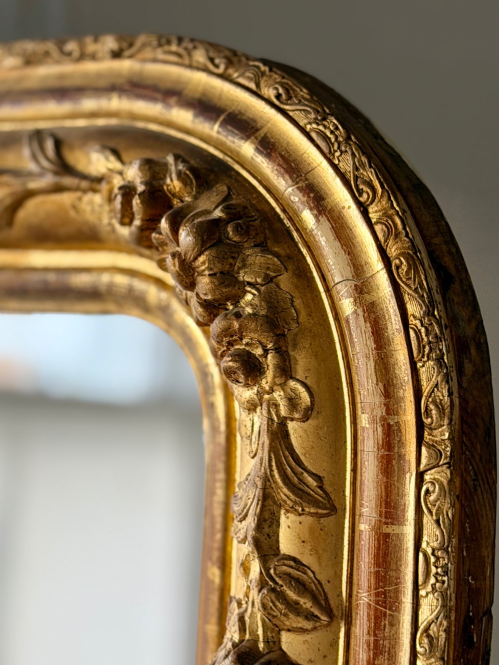 A large 19th-century French Louis Philippe mirror featuring a gilded wood frame with rounded top corners and foxed mercury glass. View II