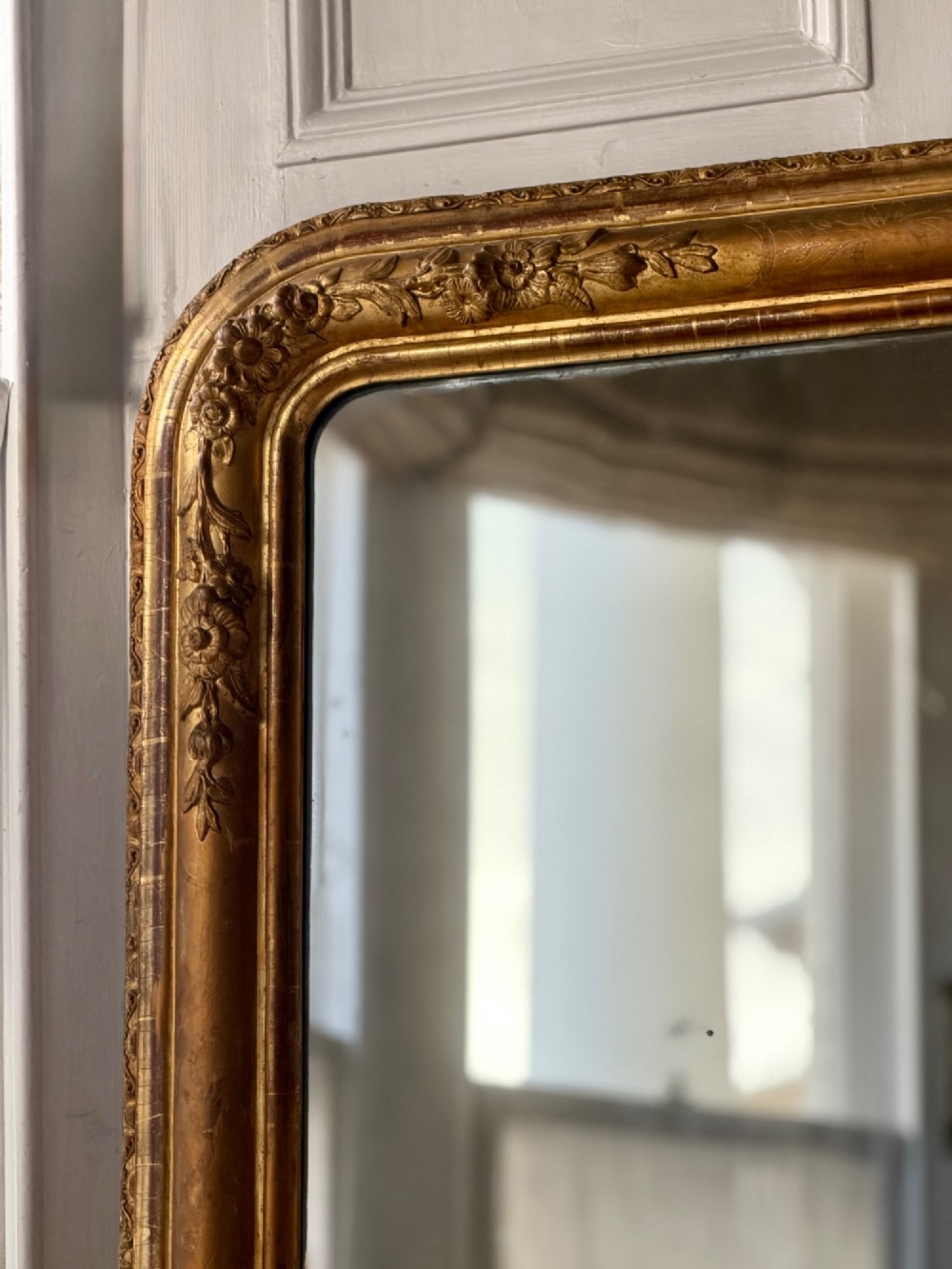 A large 19th-century French Louis Philippe mirror featuring a gilded wood frame with rounded top corners and foxed mercury glass. View V