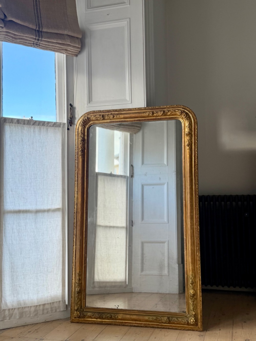 A large 19th-century French Louis Philippe mirror featuring a gilded wood frame with rounded top corners and foxed mercury glass. View VIII