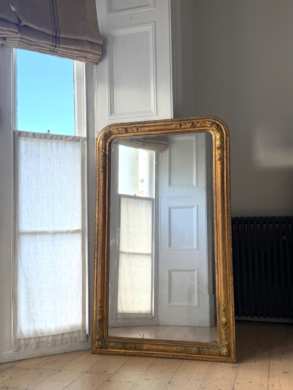 A large 19th-century French Louis Philippe mirror featuring a gilded wood frame with rounded top corners and foxed mercury glass. View IX