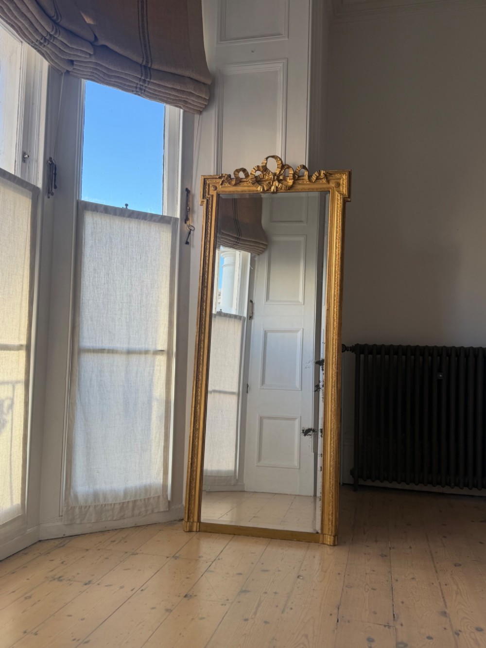 A tall rectangular gold giltwood full-length mirror featuring a carved bow ribbon cresting, beaded inner frame, and bevelled glass plate. View II