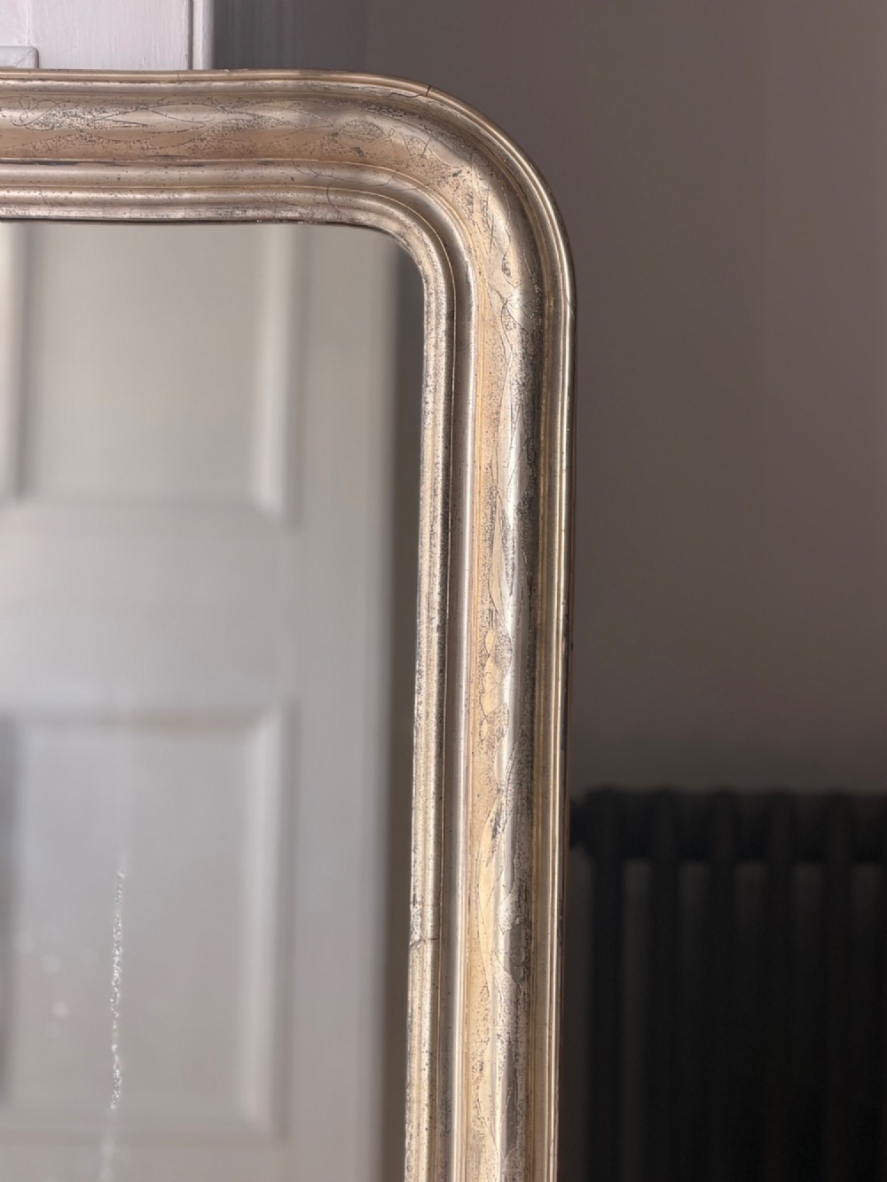 A tall rectangular antique French mirror featuring rounded top corners and a simple silver gilt frame. View III