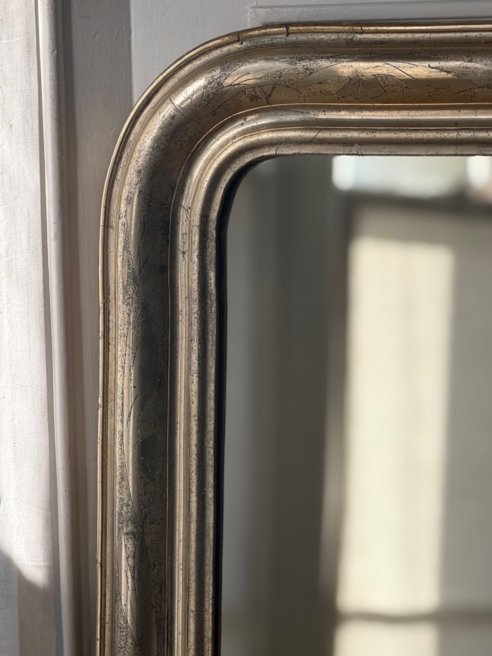 A tall rectangular antique French mirror featuring rounded top corners and a simple silver gilt frame. View V