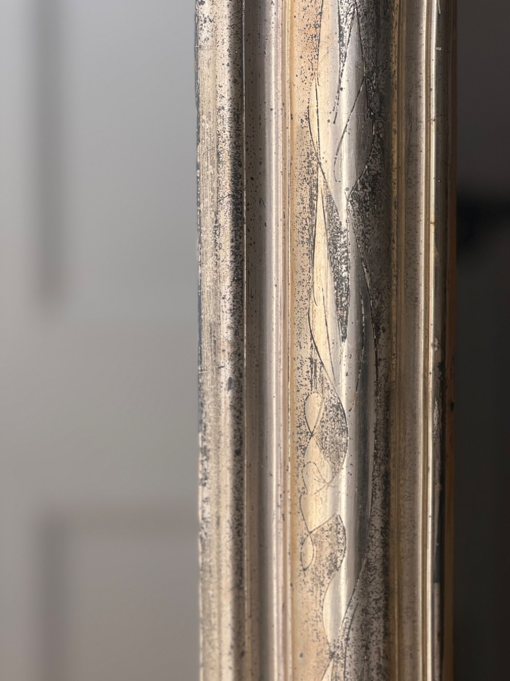 A tall rectangular antique French mirror featuring rounded top corners and a simple silver gilt frame. View VI