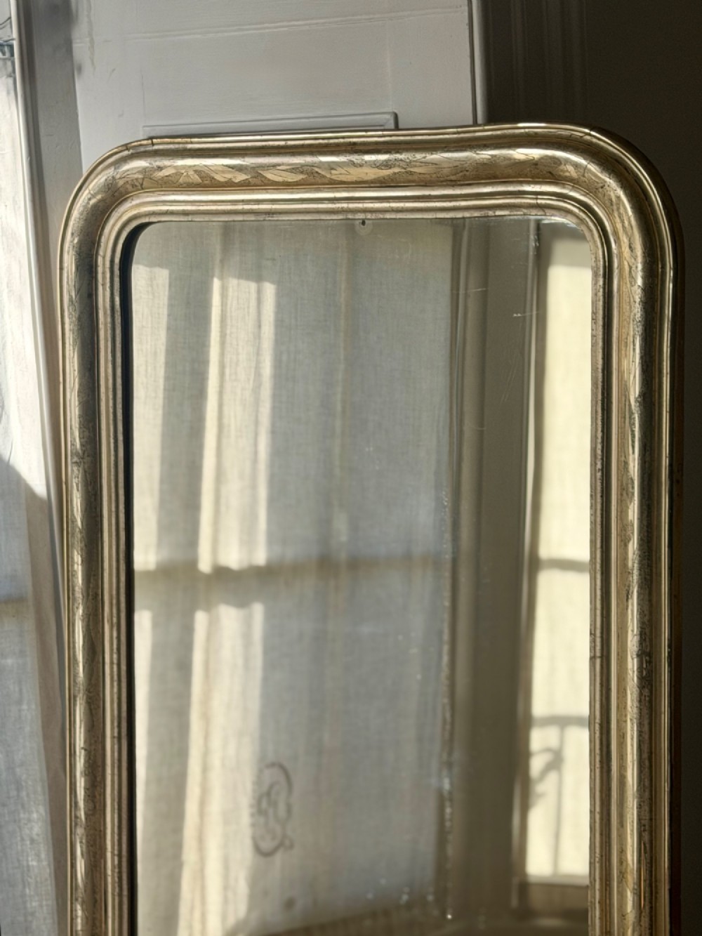 A tall rectangular antique French mirror featuring rounded top corners and a simple silver gilt frame. View VII