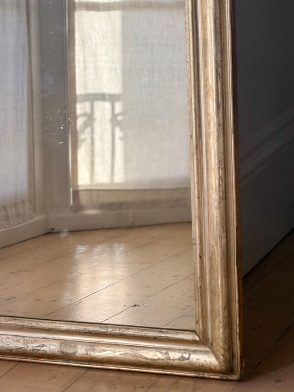 A tall rectangular antique French mirror featuring rounded top corners and a simple silver gilt frame. View IX