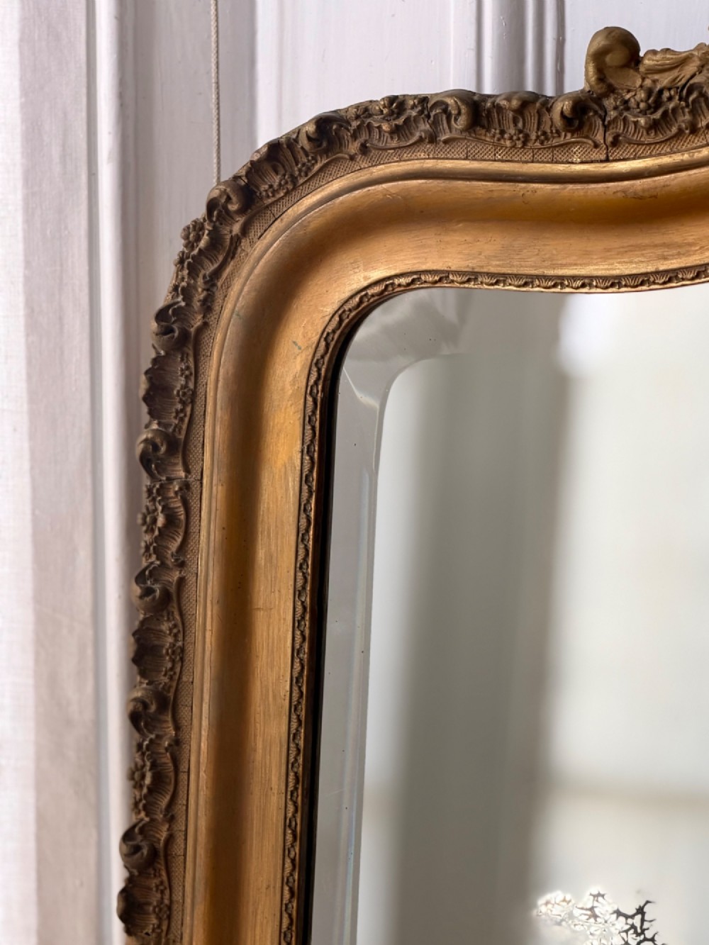 A large French Louis XV style giltwood mirror featuring an arched top crest with carved scrollwork and a bevelled mirror plate. View III