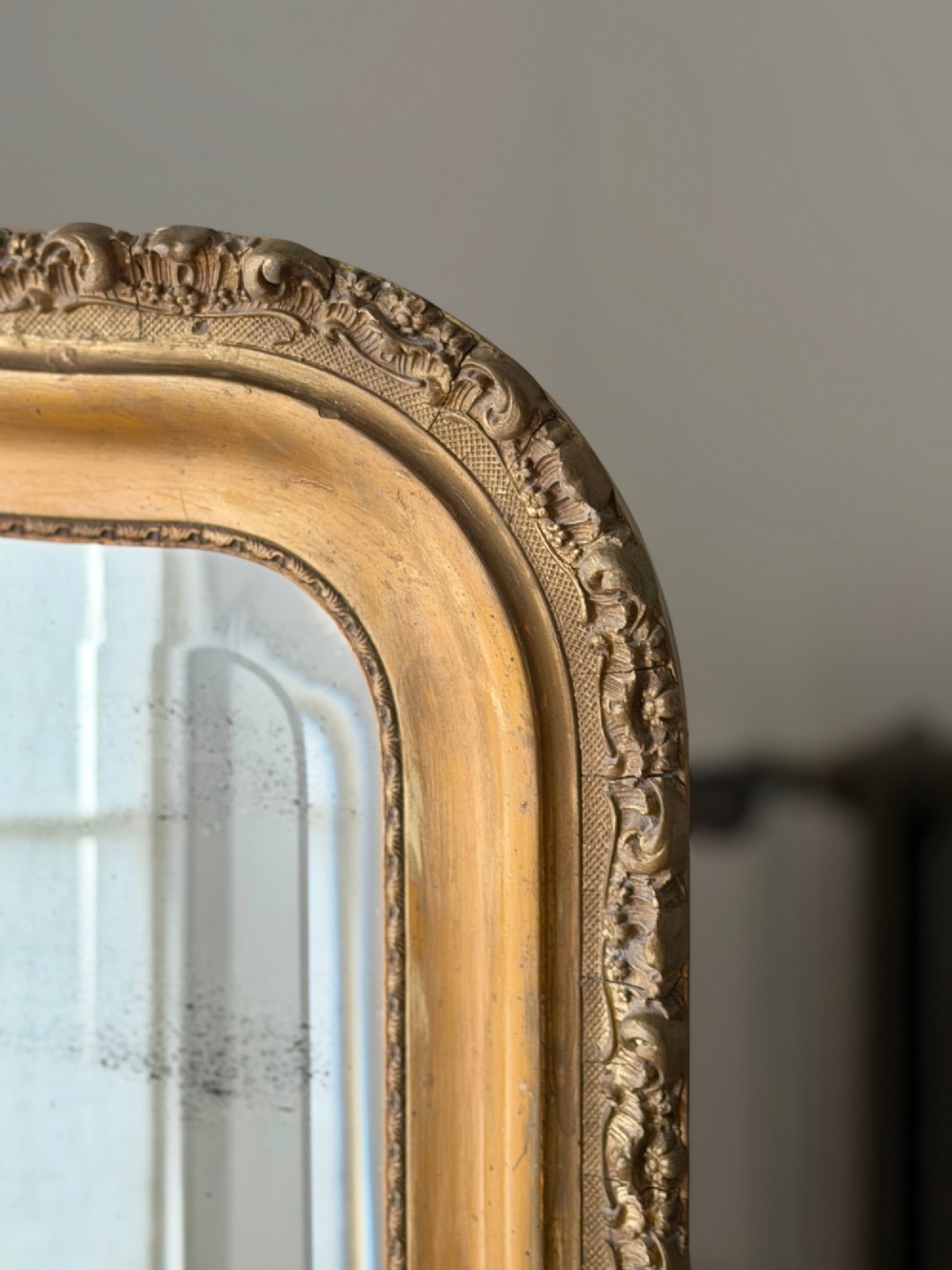 A large French Louis XV style giltwood mirror featuring an arched top crest with carved scrollwork and a bevelled mirror plate. View VII