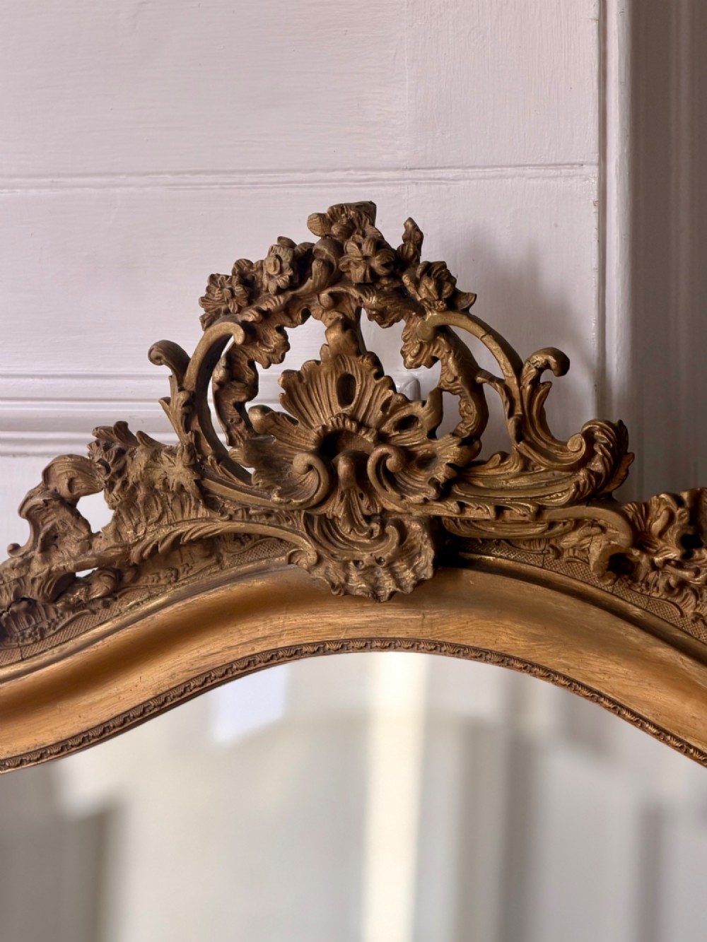 A large French Louis XV style giltwood mirror featuring an arched top crest with carved scrollwork and a bevelled mirror plate. View VIII