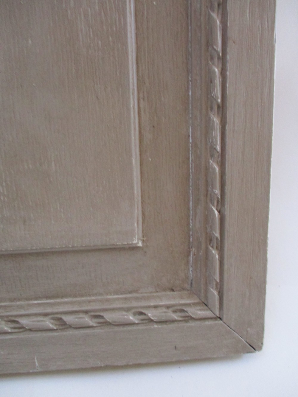 A pair of grey painted wooden cabinet doors decorated with hand-carved laurel wreaths and ribbon swags. View V