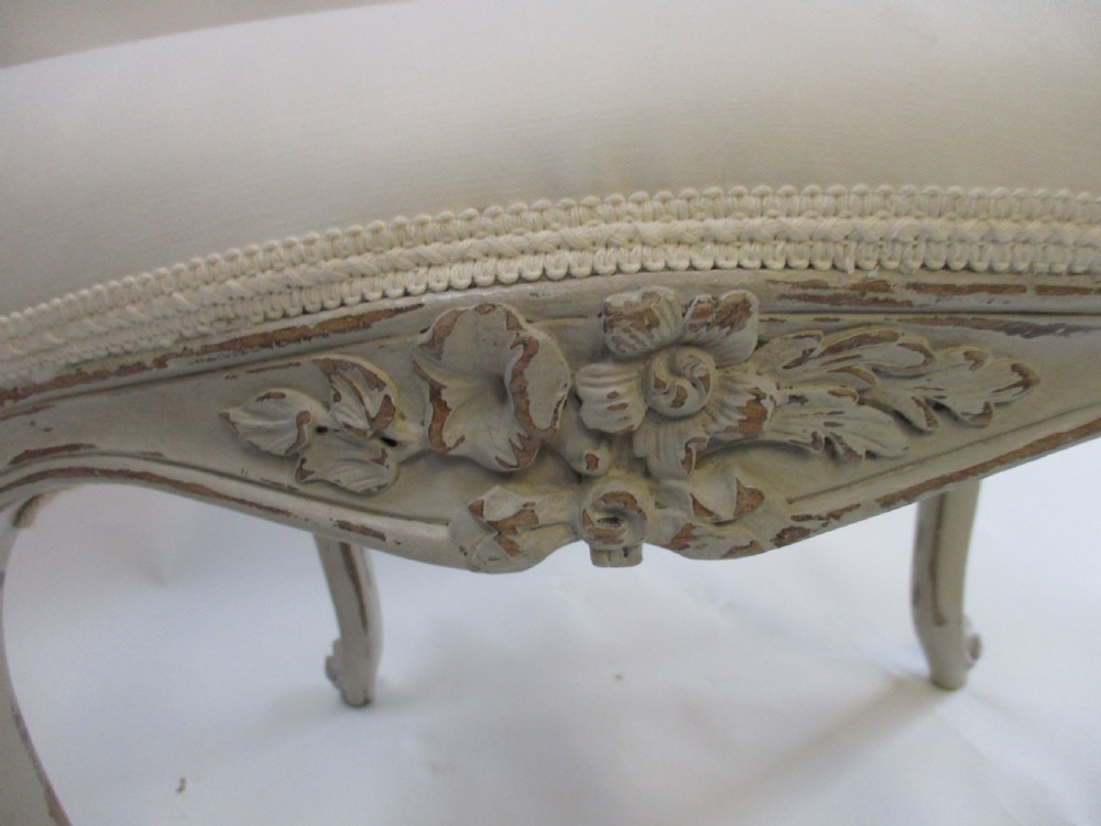 A French Louis XV style rectangular stool with hand-carved floral aprons, distressed grey cabriole legs, and a cream upholstered top. View III