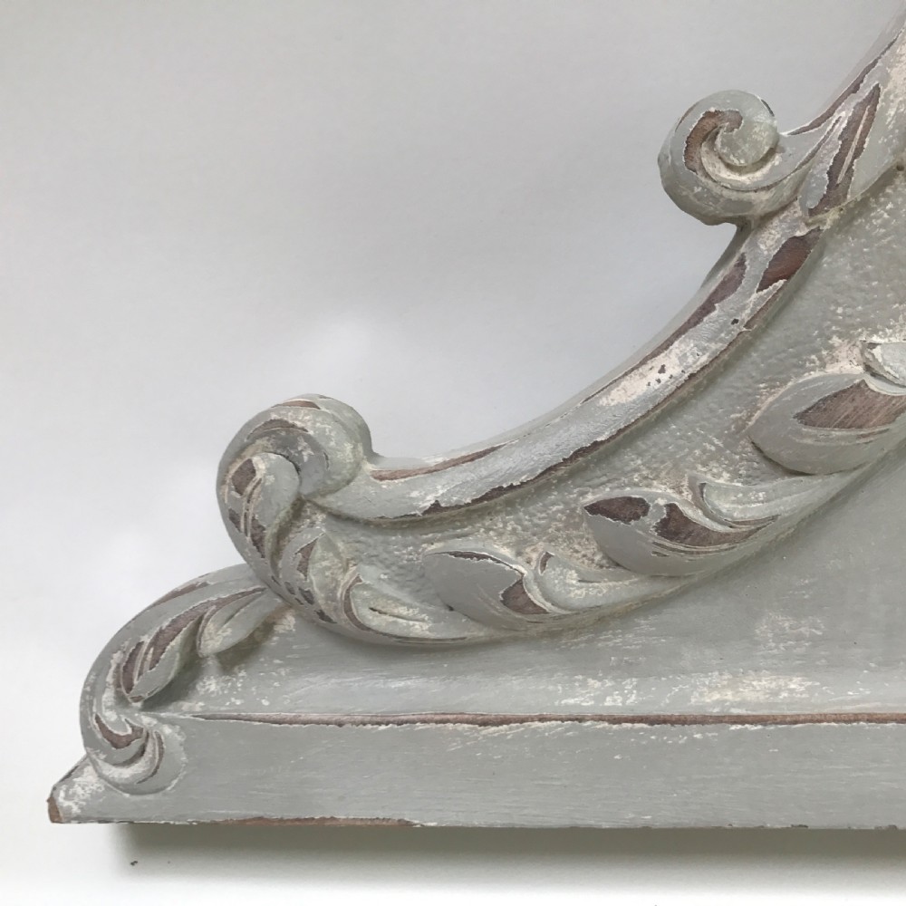 A carved wooden architectural pelmet featuring central scroll motifs and a distressed grey painted finish. View III