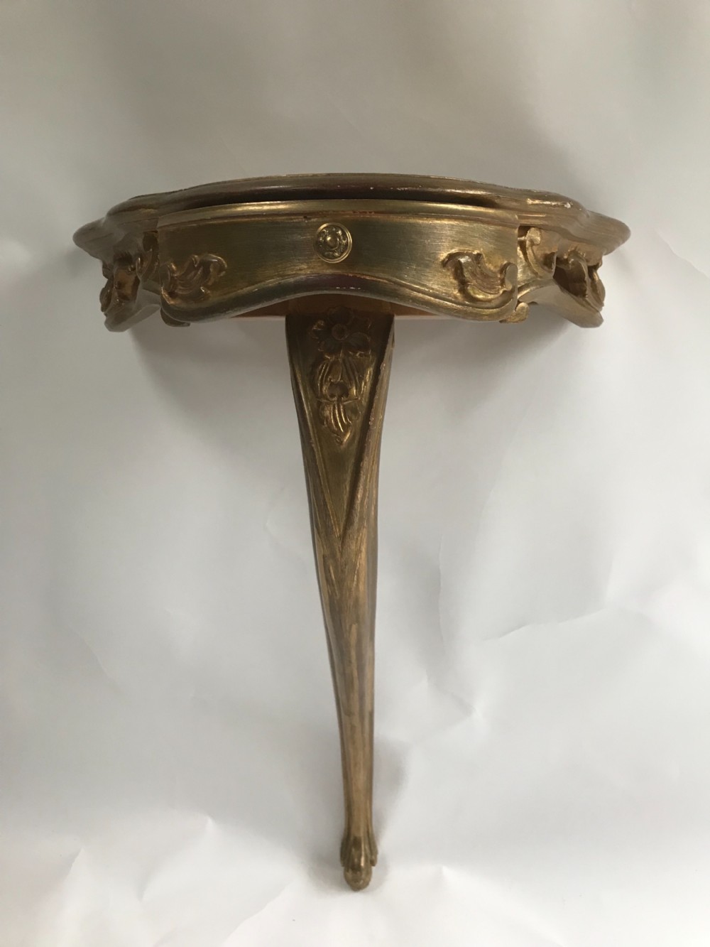 A pair of wall-mounted Italian giltwood console tables with serpentine tops, carved floral aprons, and single cabriole legs. View V