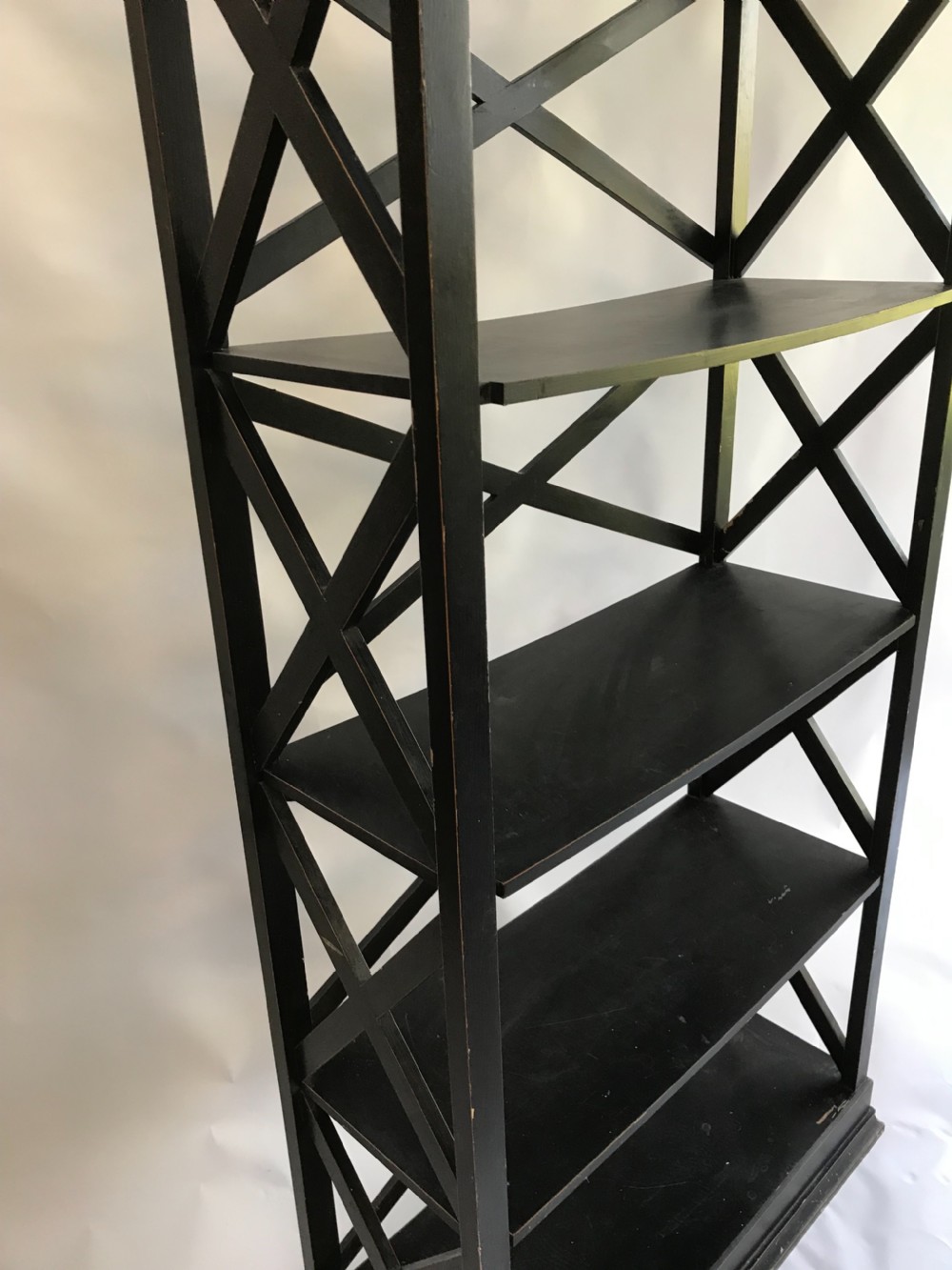 A tall, freestanding black painted open shelving unit featuring five horizontal tiers, X-frame lattice sides, a moulded top cornice, and a plinth base. View II