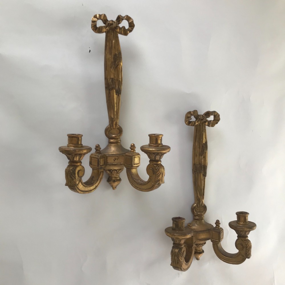A pair of French carved giltwood wall lights featuring ribbon bow backplates and two scrolling candle arms with acanthus leaf decoration. View II