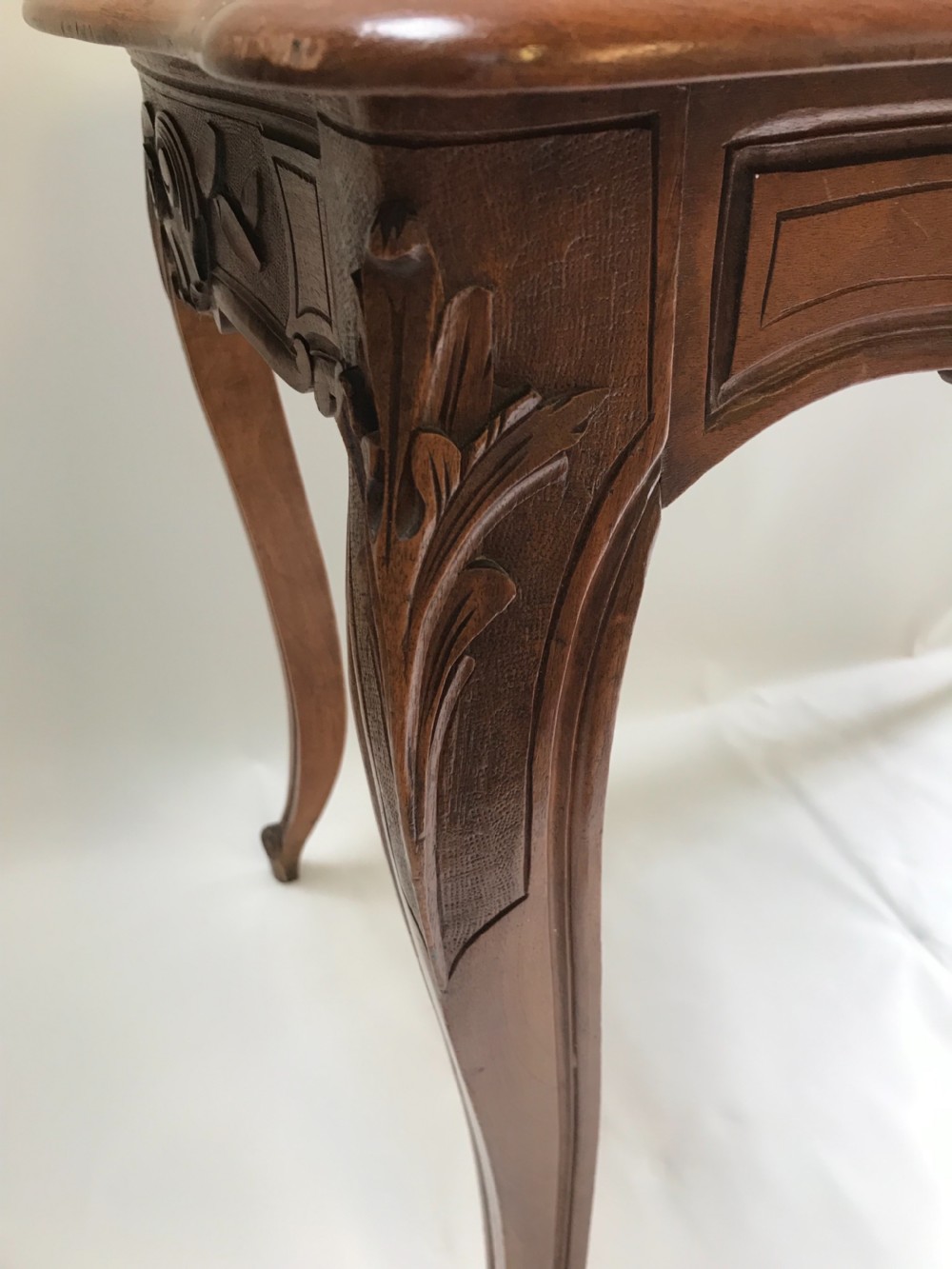 An antique French walnut centre table featuring carved floral frieze detailing and slender cabriole legs with a serpentine top. View III