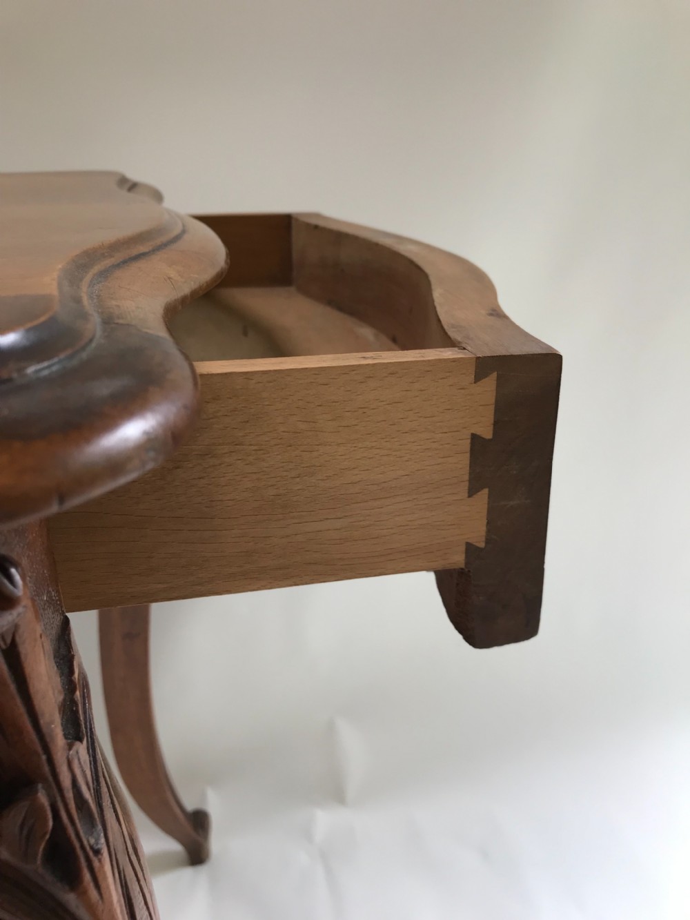 An antique French walnut centre table featuring carved floral frieze detailing and slender cabriole legs with a serpentine top. View IV