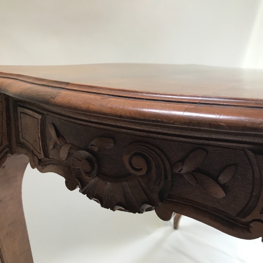 An antique French walnut centre table featuring carved floral frieze detailing and slender cabriole legs with a serpentine top. View VI