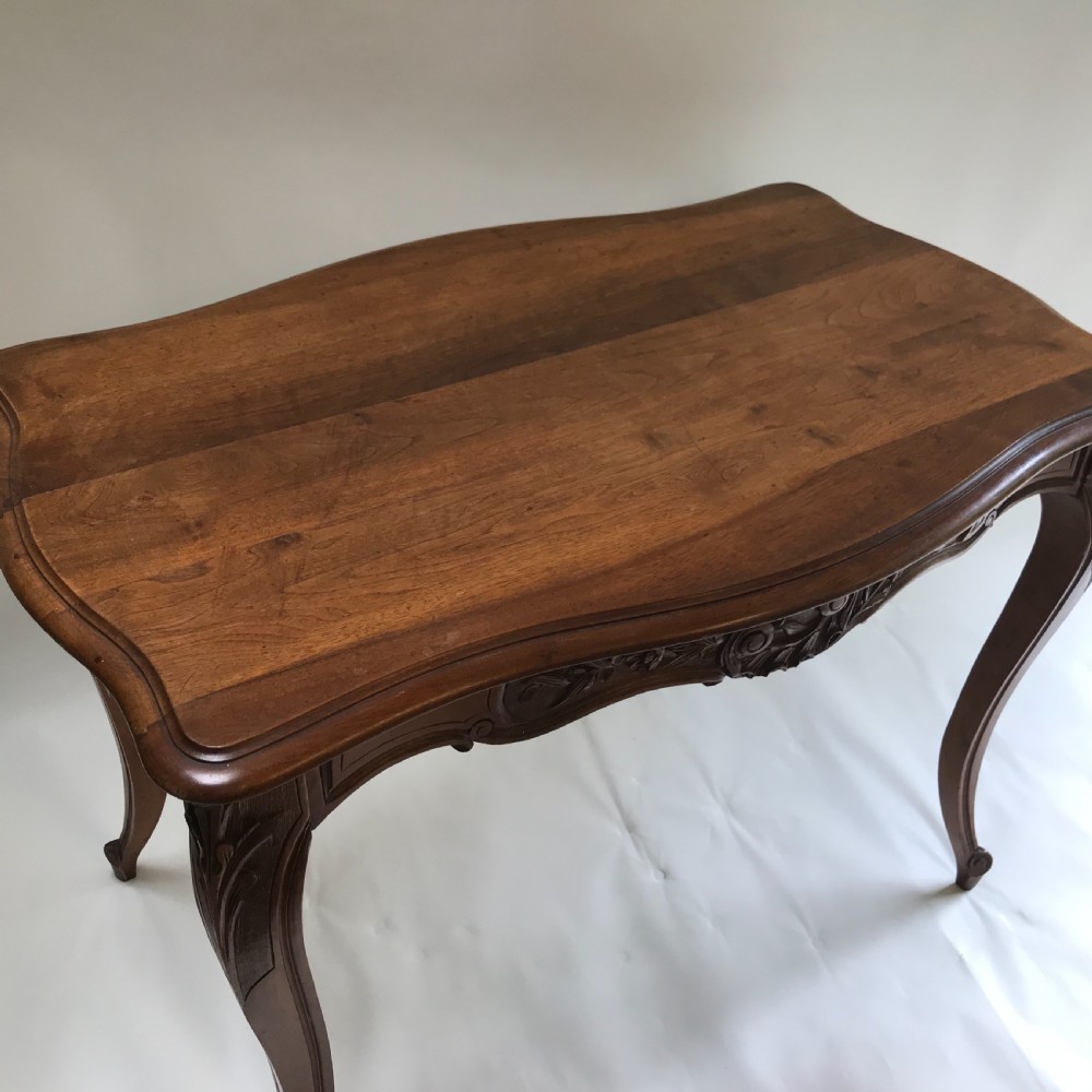 An antique French walnut centre table featuring carved floral frieze detailing and slender cabriole legs with a serpentine top. View VII
