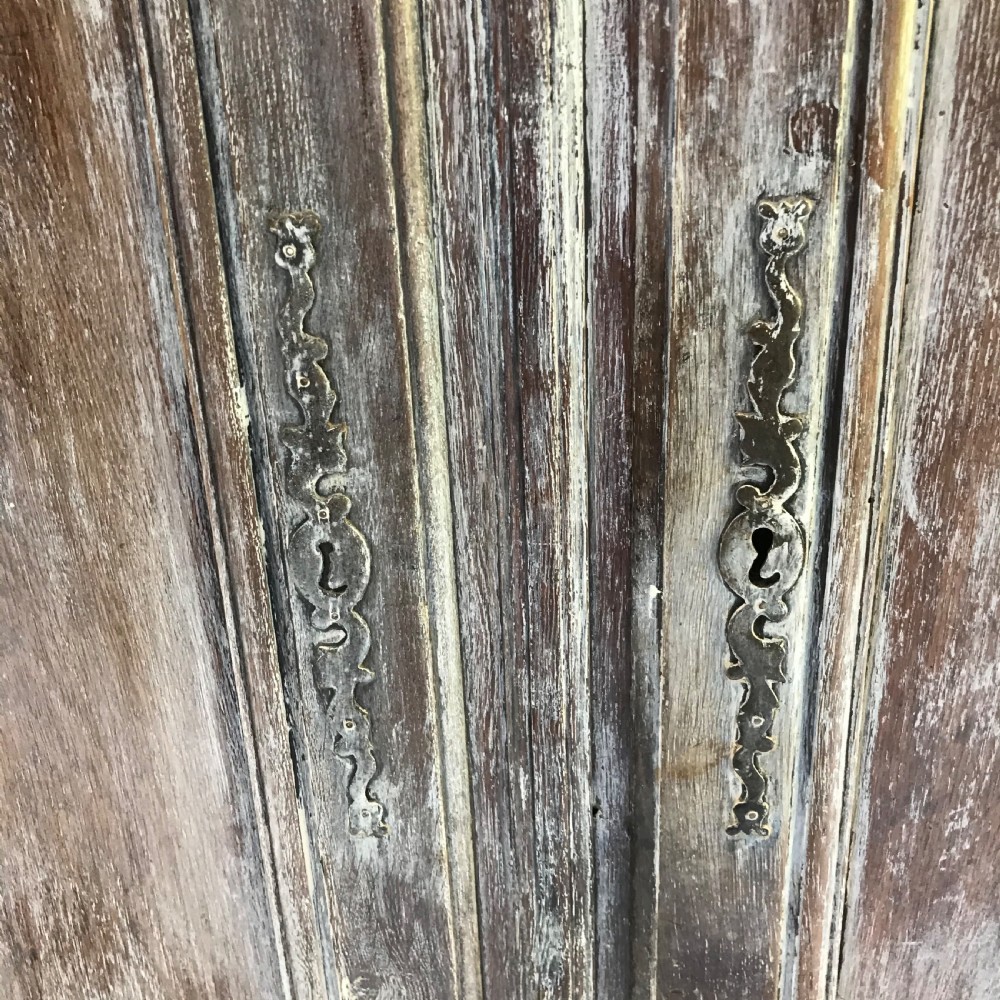 A pair of antique French carved wooden doors featuring a distressed grey painted finish, moulded serpentine panels, and original iron hinges. View III