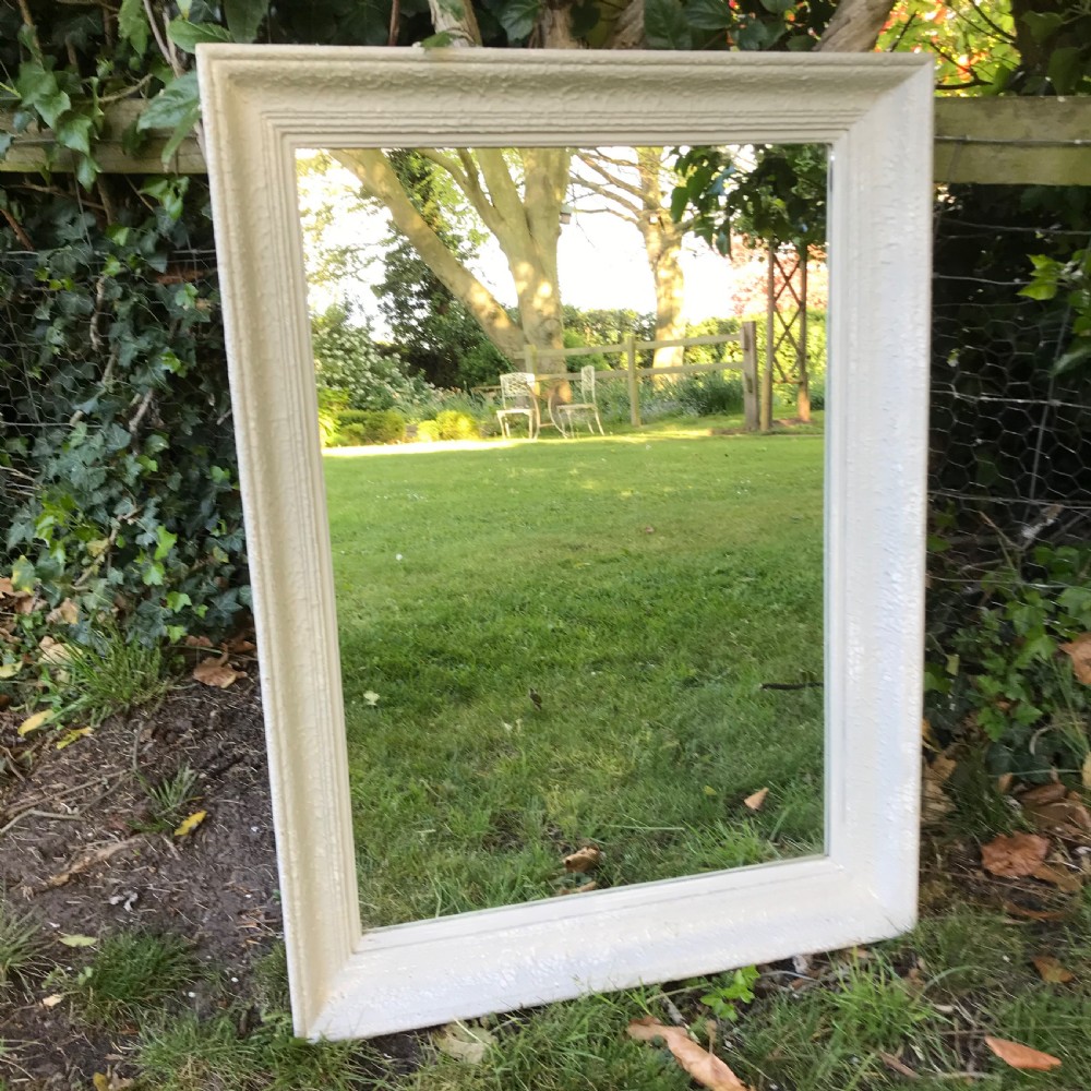 A rectangular off-white painted French framed wall mirror featuring a moulded timber border and reflective glass plate.