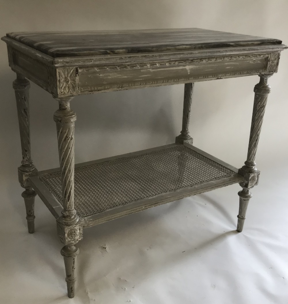 A French Neoclassical style painted wooden side table featuring a dark striated marble top, spiral turned legs, and a woven cane lower shelf. View II