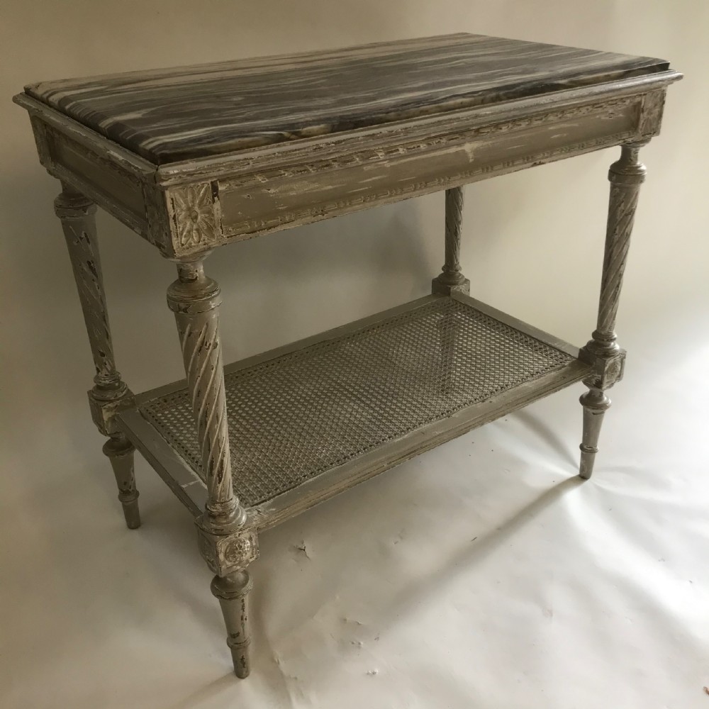 A French Neoclassical style painted wooden side table featuring a dark striated marble top, spiral turned legs, and a woven cane lower shelf. View IX