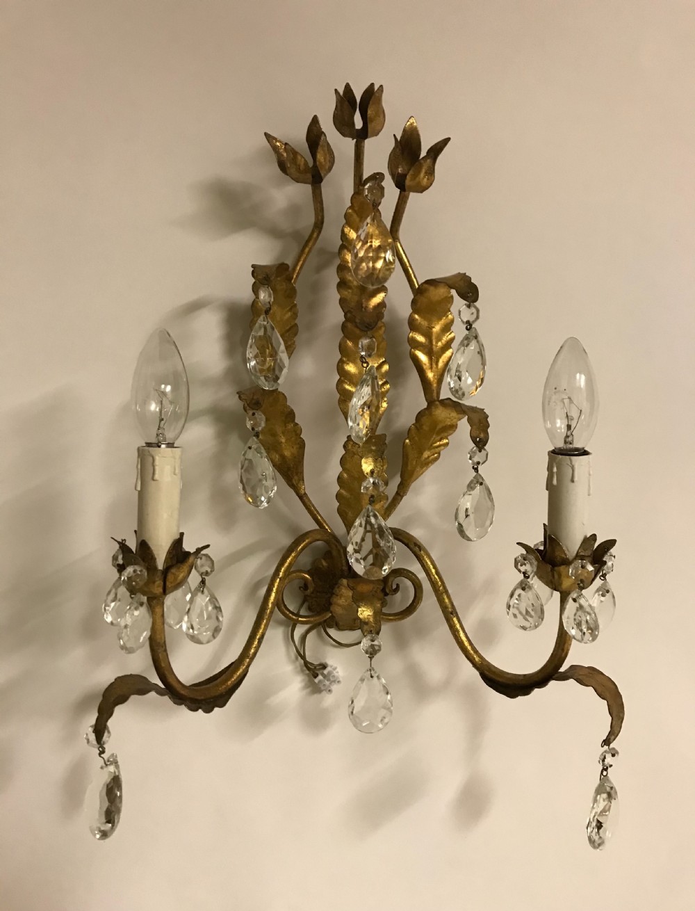 A pair of gilded metal two-arm wall sconces decorated with leaf forms, tulip-shaped flower candle sockets, and suspended clear crystal drops. View II